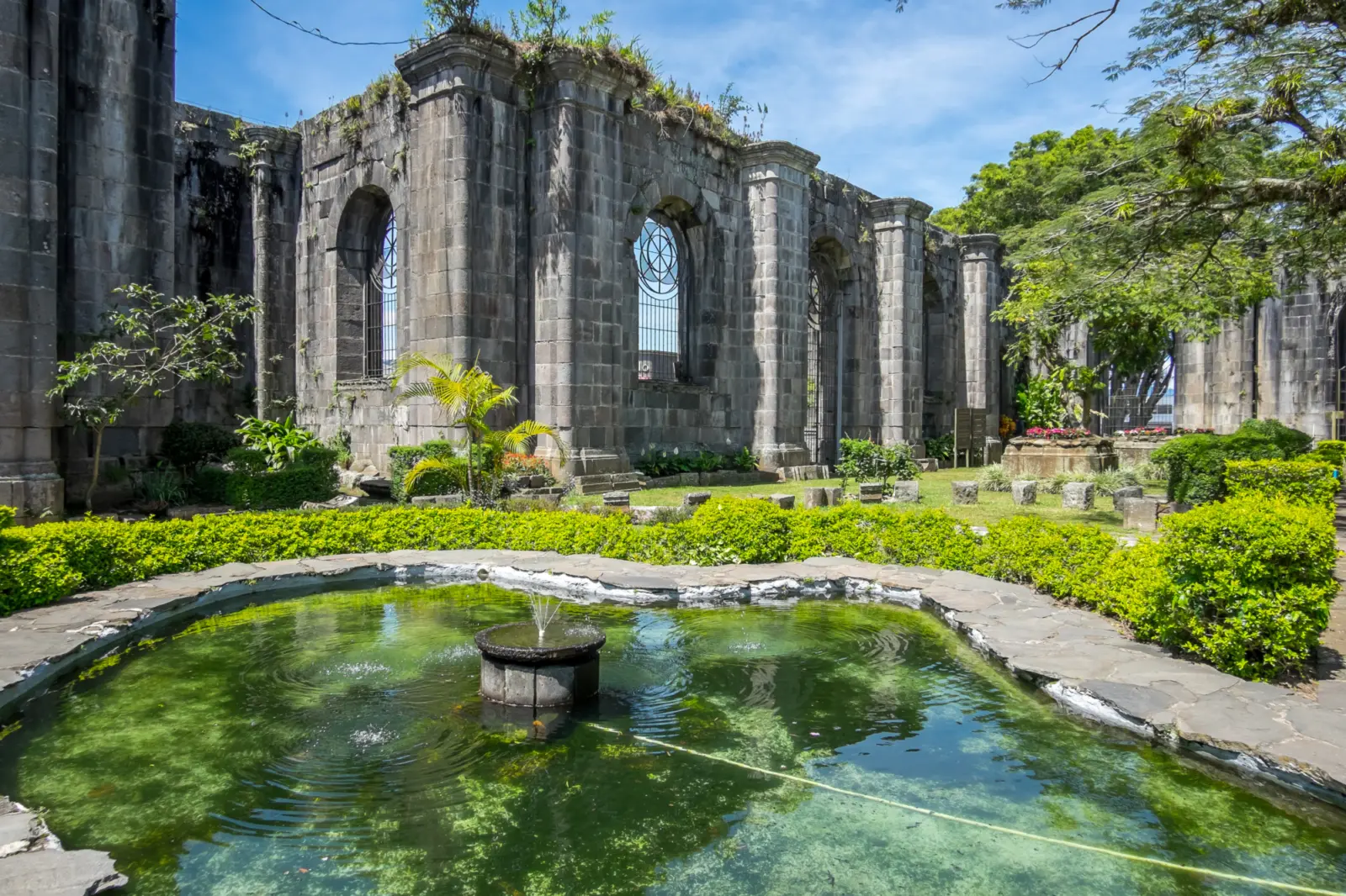 Des ruines entourées de verdure avec un bassin d'eau