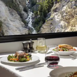 Un repas gastronomique servi à bord du wagon-restaurant GoldLeaf du train de luxe Rocky Mountaineer, alors qu'il traverse les paysages montagneux des Rocheuses canadiennes