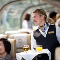 Une hôtesse assurant le service à bord du train Rocky Mountaineer dans un wagon de la classe de service GoldLeaf