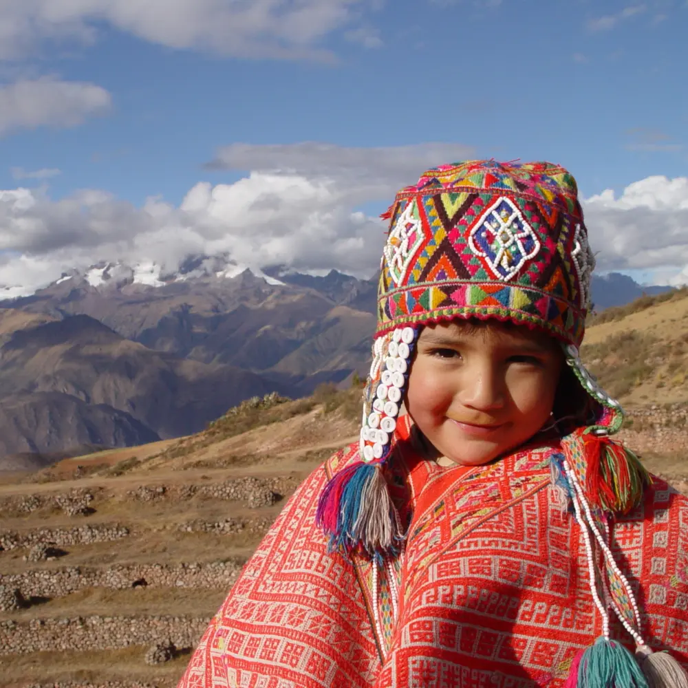 Un jeune garçon péruvien en habit traditionnel coloré dans les montagnes