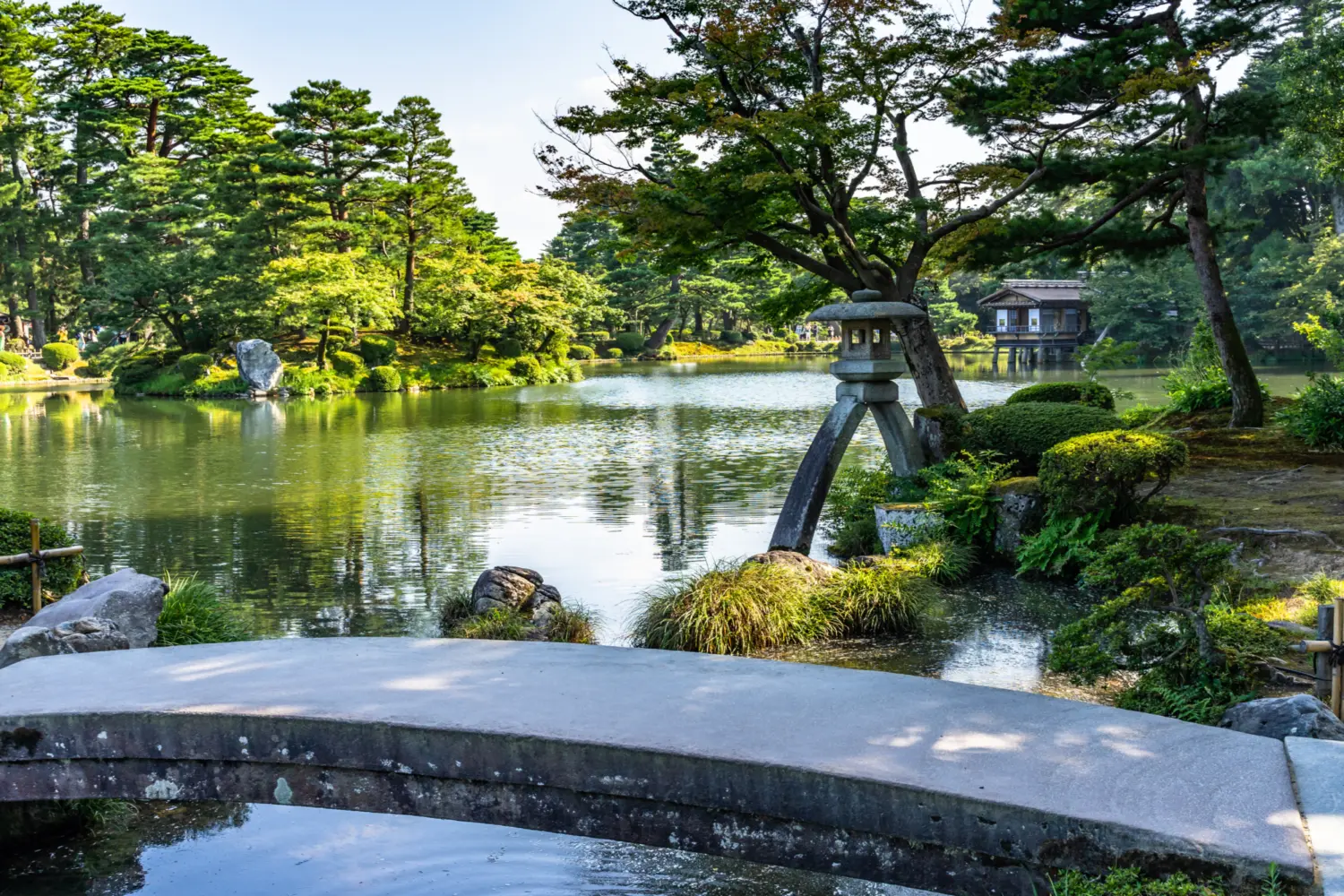 Un pont de pierre au-dessus d'un étang dans un jardin japonais