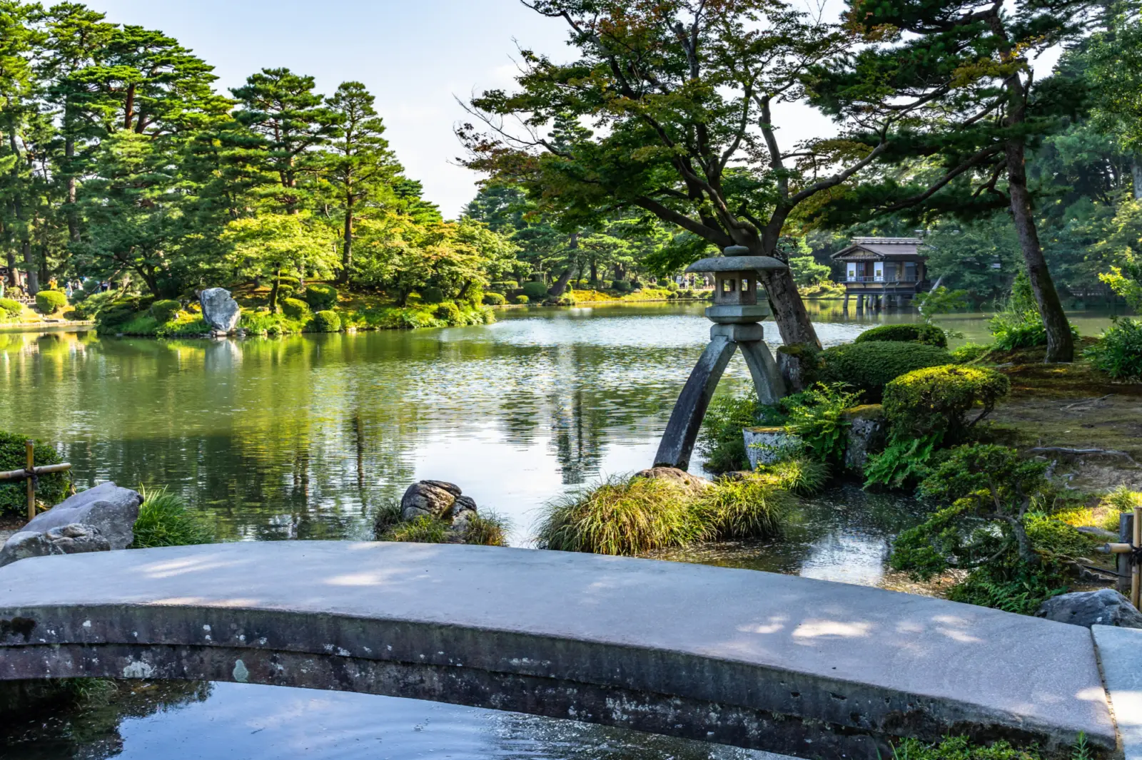 Un pont de pierre au-dessus d'un étang dans un jardin japonais