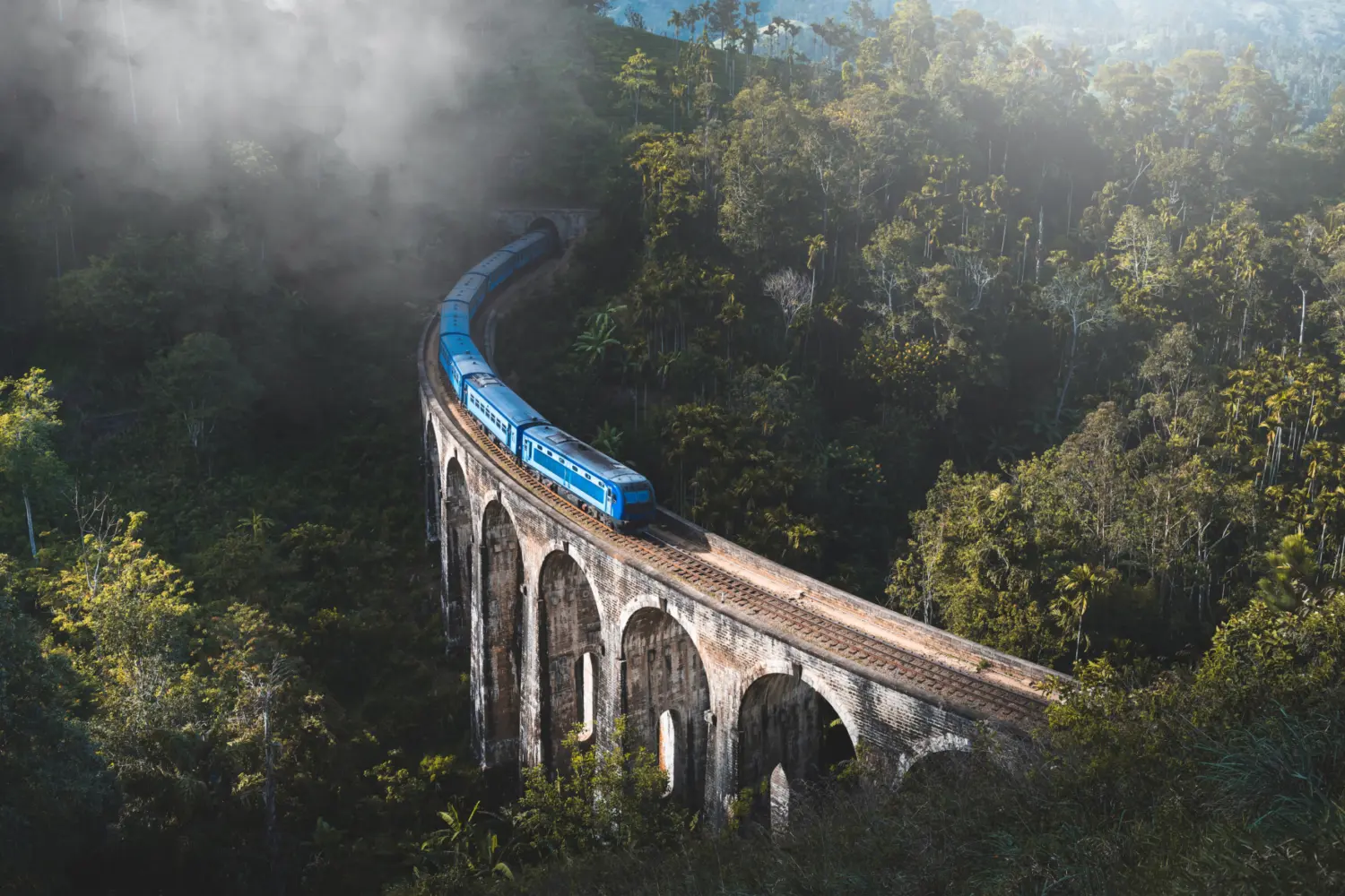 Un train traversant un pont avec plusieurs arches dans les montagnes du Sri Lanka