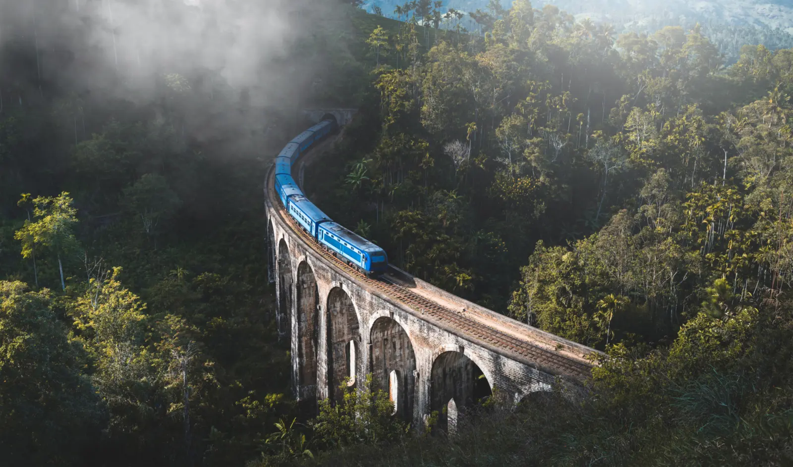 Un train traversant un pont avec plusieurs arches dans les montagnes du Sri Lanka