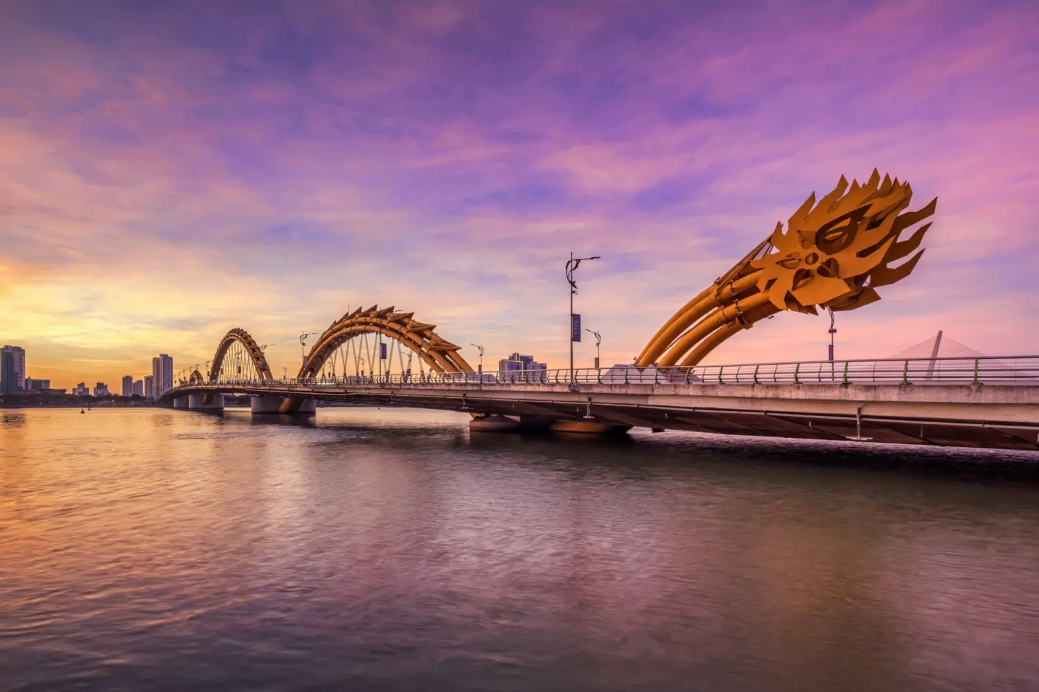 Un pont avec une sculpture de dragon au coucher du soleil