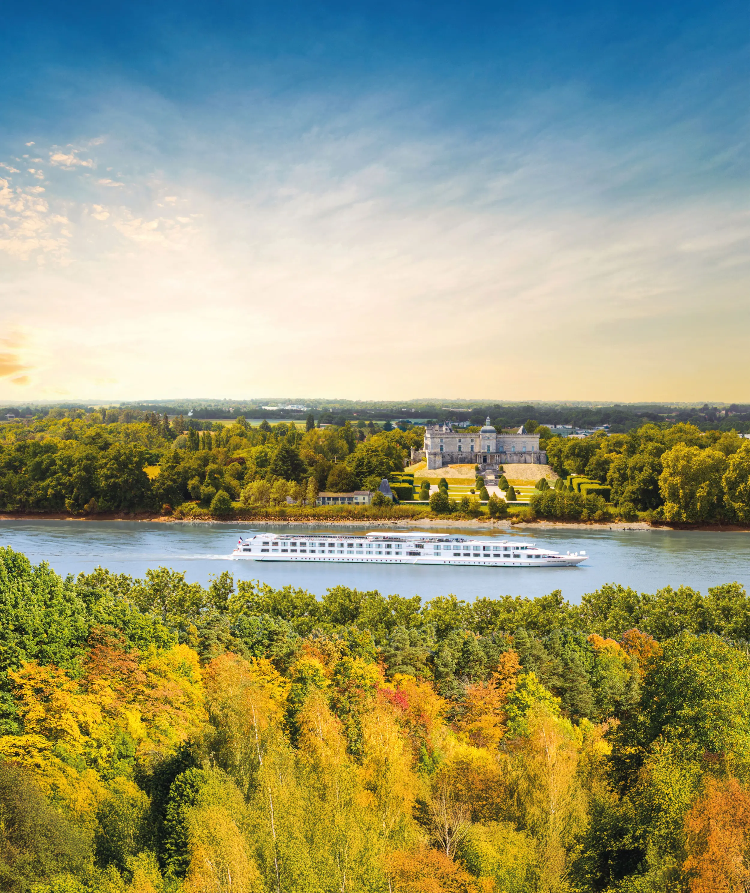 Un navire de croisière fluviale de la compagnie CroisiEurope naviguant sur un fleuve en face d'un château historique entouré d'arbres aux couleurs d'automne