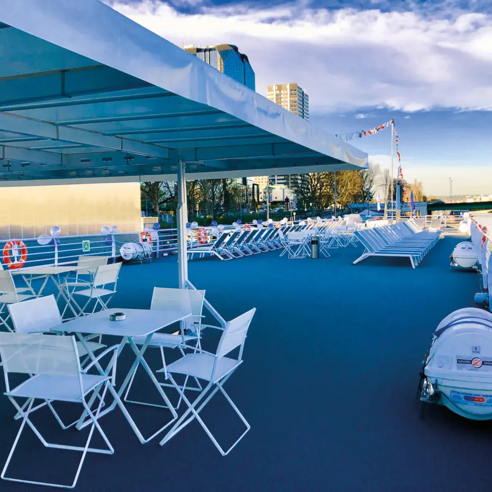 Un pont avec chaises et tables sur un bateau naviguant sur l'eau