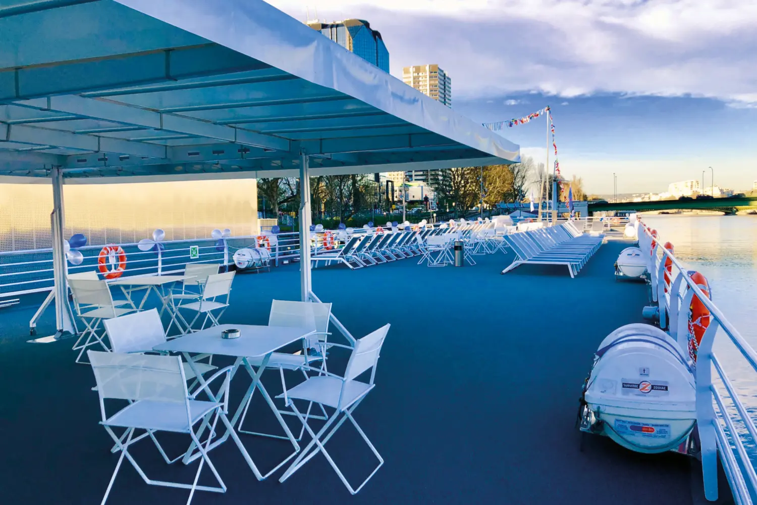 Un pont avec chaises et tables sur un bateau naviguant sur l'eau