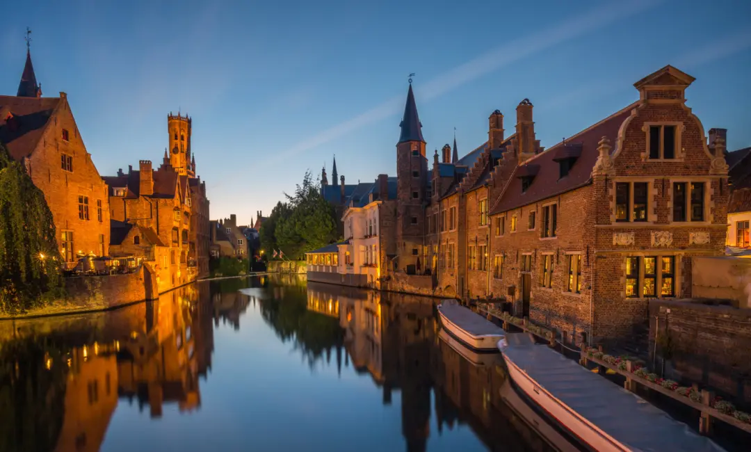 Un canal avec des maisons en pierre illuminé en soirée, à Bruges en Belgique