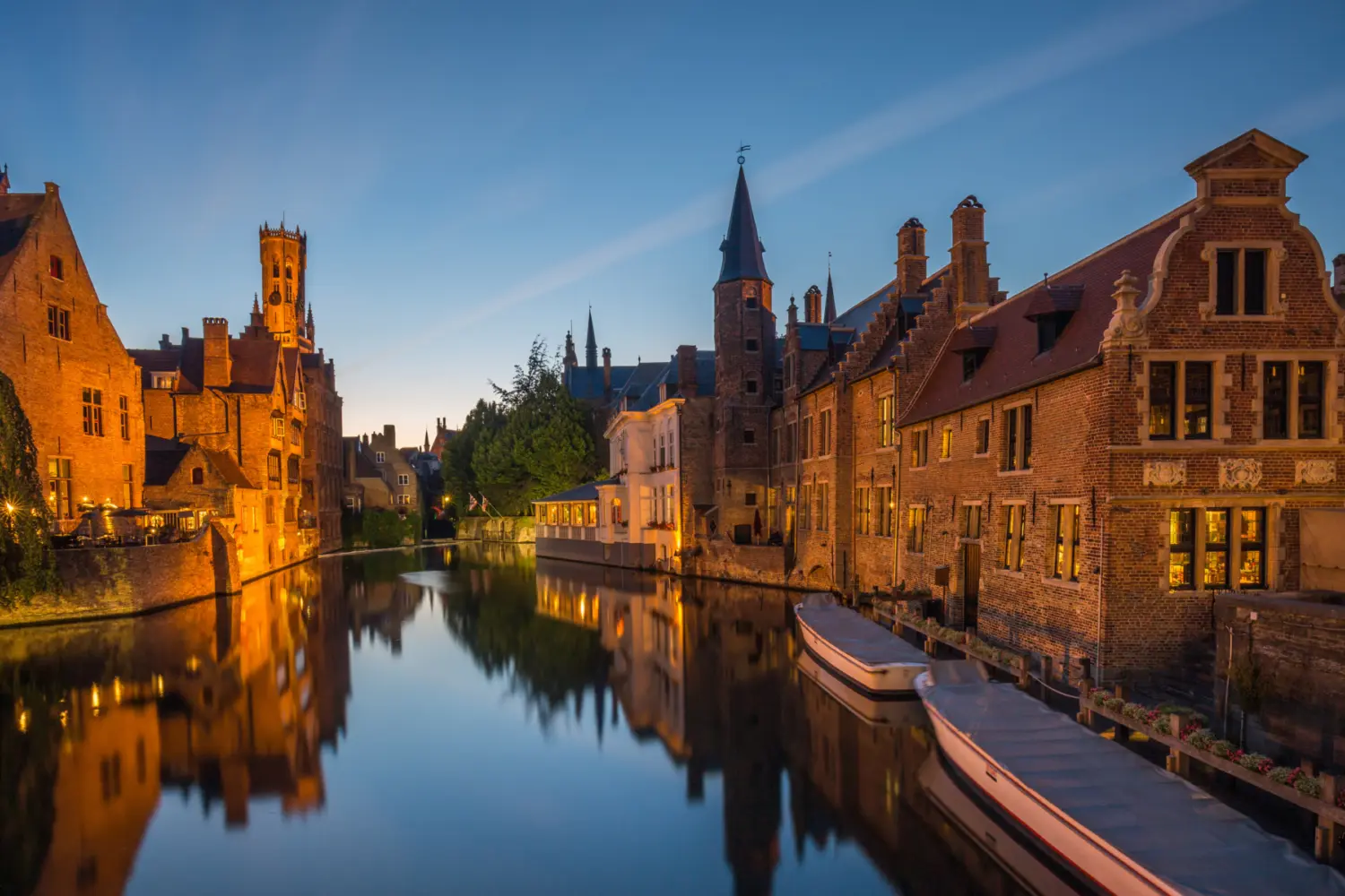 Un canal avec des maisons en pierre illuminé en soirée, à Bruges en Belgique