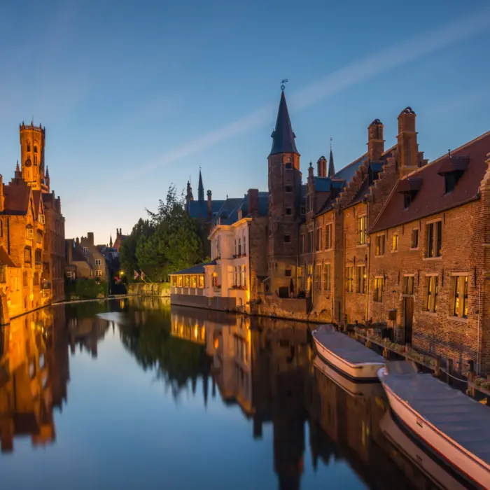 Un canal avec des maisons en pierre illuminé en soirée, à Bruges en Belgique