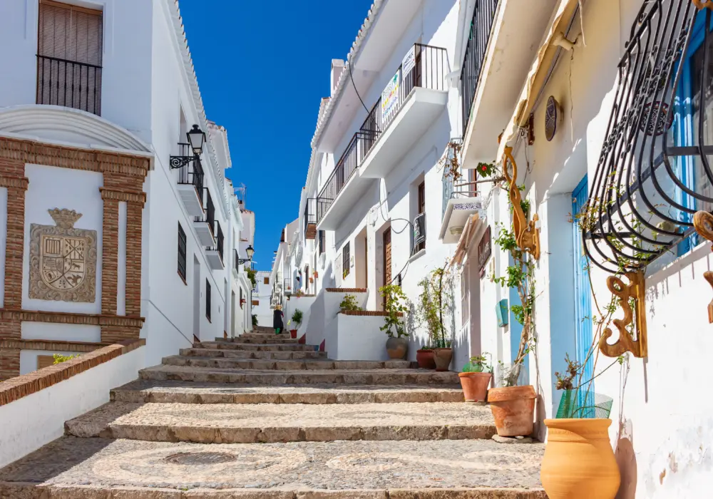 Ruelle pavée en pente bordée de maisons blanchies à la chaux dans le village de Frigiliana, situé en Andalousie, en Espagne