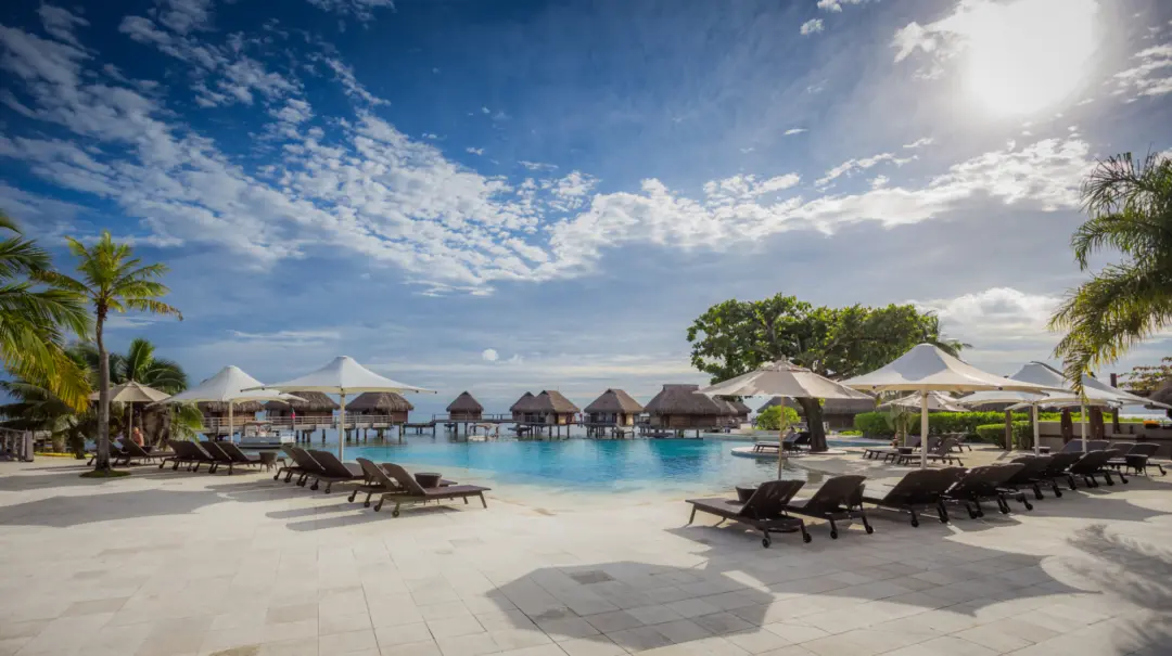 Vue vers l'océan de la piscine et des chaises longues du Manava Beach Resort & Spa Hotel Moorea en Polynésie française