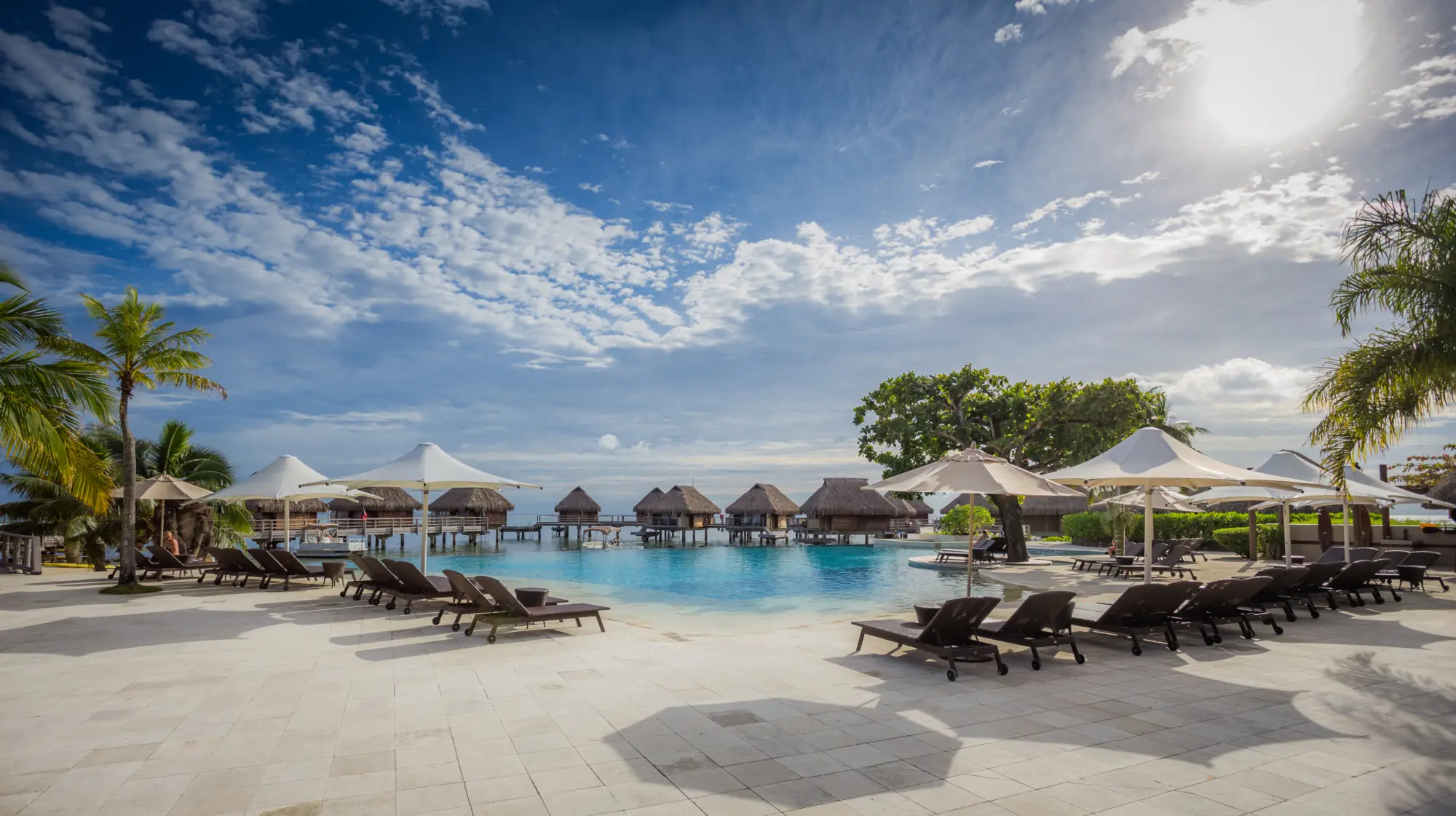 Vue vers l'océan de la piscine et des chaises longues du Manava Beach Resort & Spa Hotel Moorea en Polynésie française