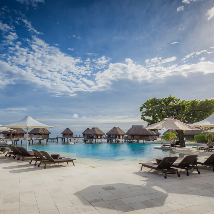 Vue vers l'océan de la piscine et des chaises longues du Manava Beach Resort & Spa Hotel Moorea en Polynésie française