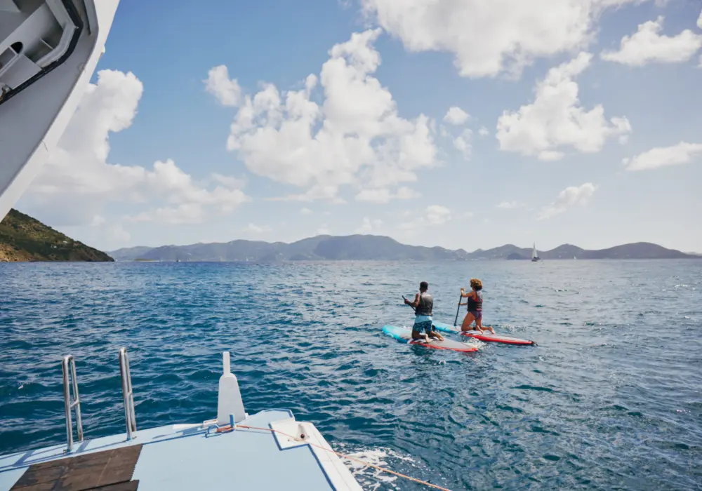 Deux personnes faisant de la planche à pagaie près d'un bateau