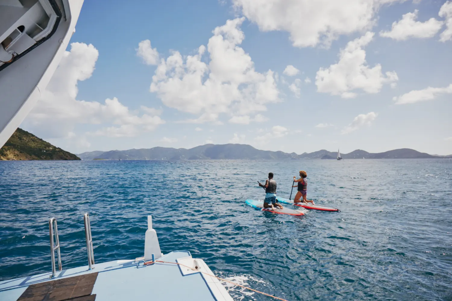 Deux personnes faisant de la planche à pagaie près d'un bateau