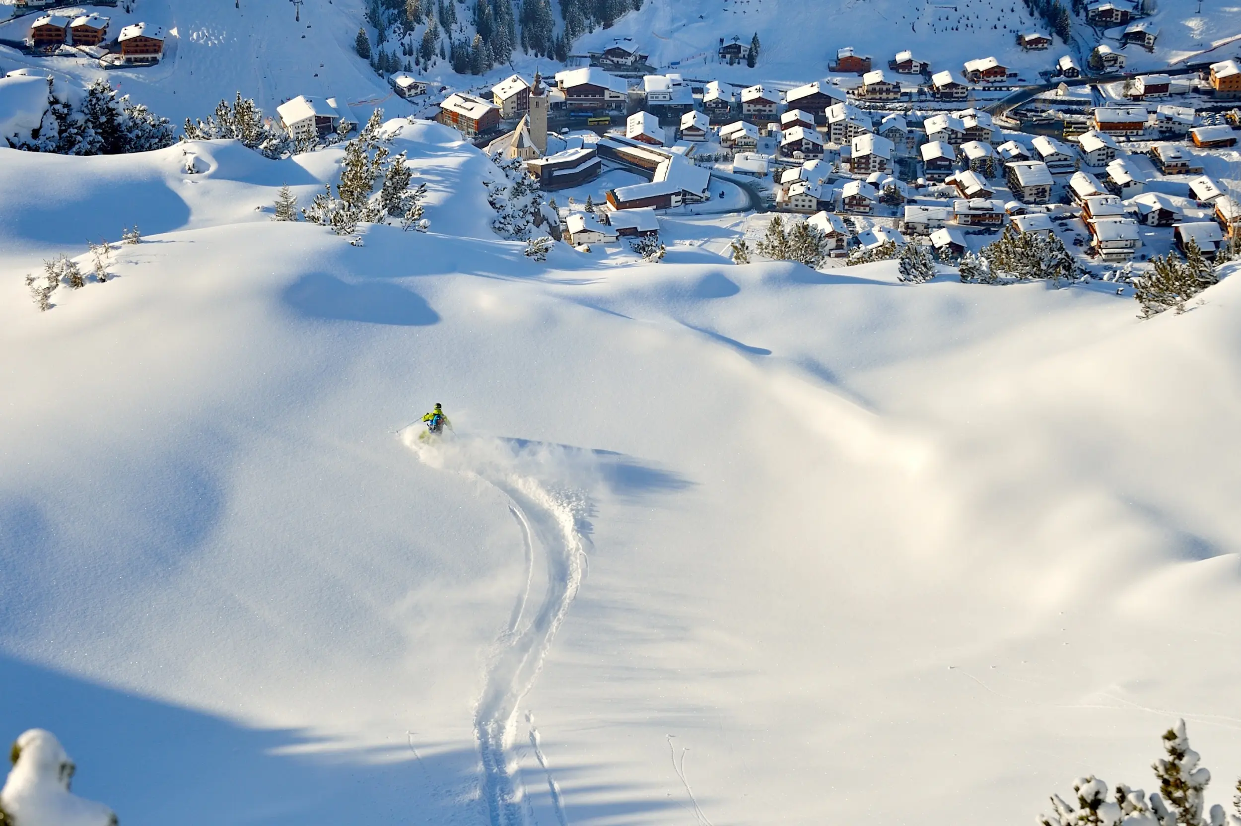 Skieur dans la neige poudreuse vers le village à la station de ski Lech Zürs en Autriche