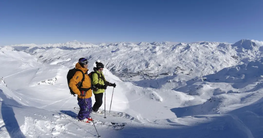 Skieurs qui profitent de la vue sur les sommets enneigés du domaine skiable des 3 Vallées au cœur des alpes françaises