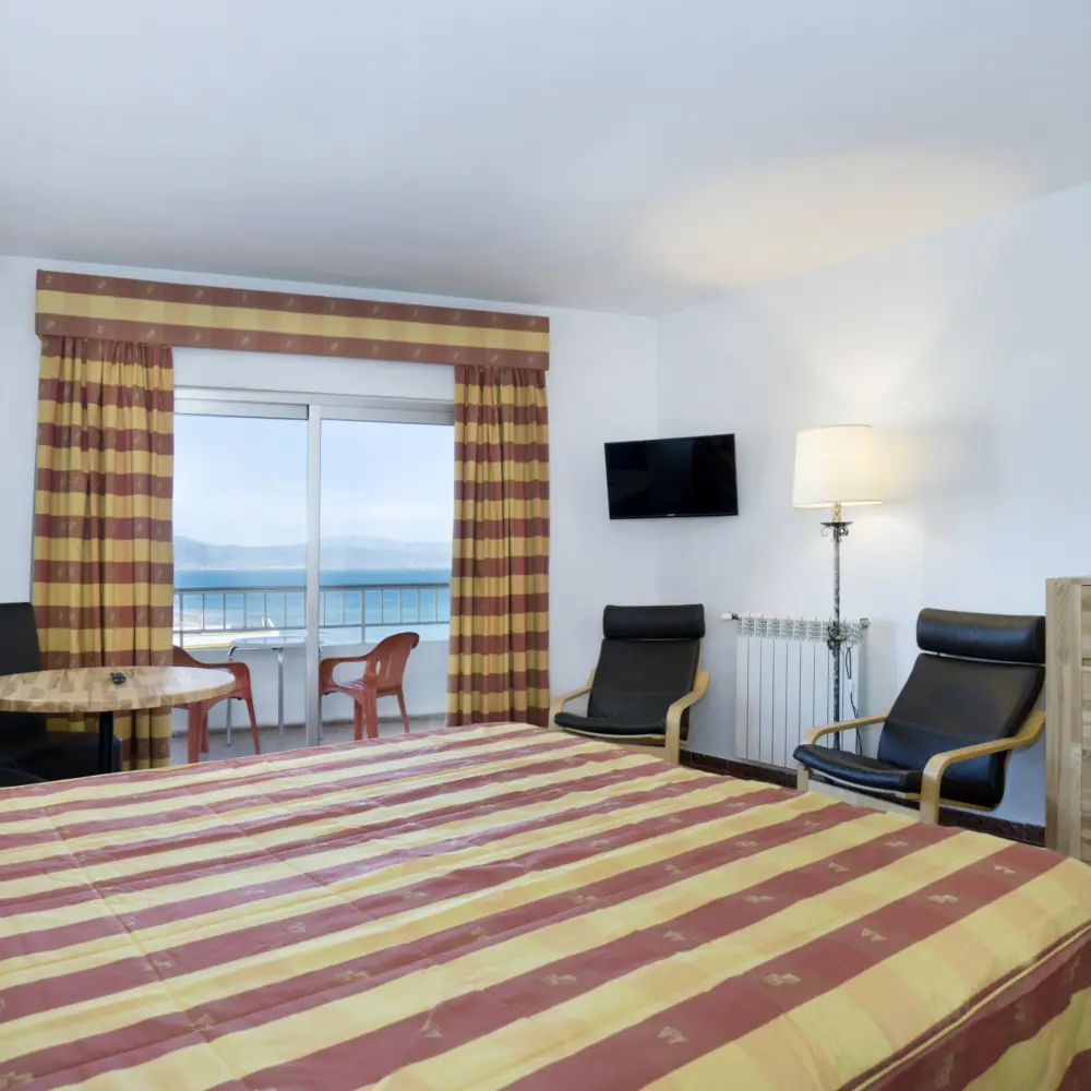 Un studio incluant lit, chaises et balcon donnant une vue sur la mer Méditerranée à l'hôtel Bajondillo à Torremolinos en Espagne