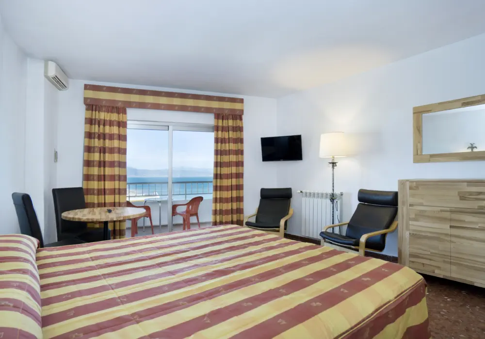 Un studio incluant lit, chaises et balcon donnant une vue sur la mer Méditerranée à l'hôtel Bajondillo à Torremolinos en Espagne