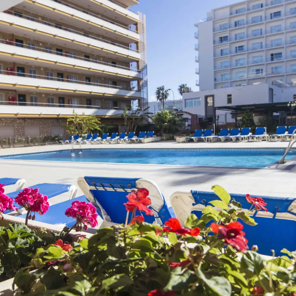 Vue sur la piscine de l'hôtel Buensol à Torremolinos en Espagne, entourée de fleurs et de chaises longues pour s'y détendre