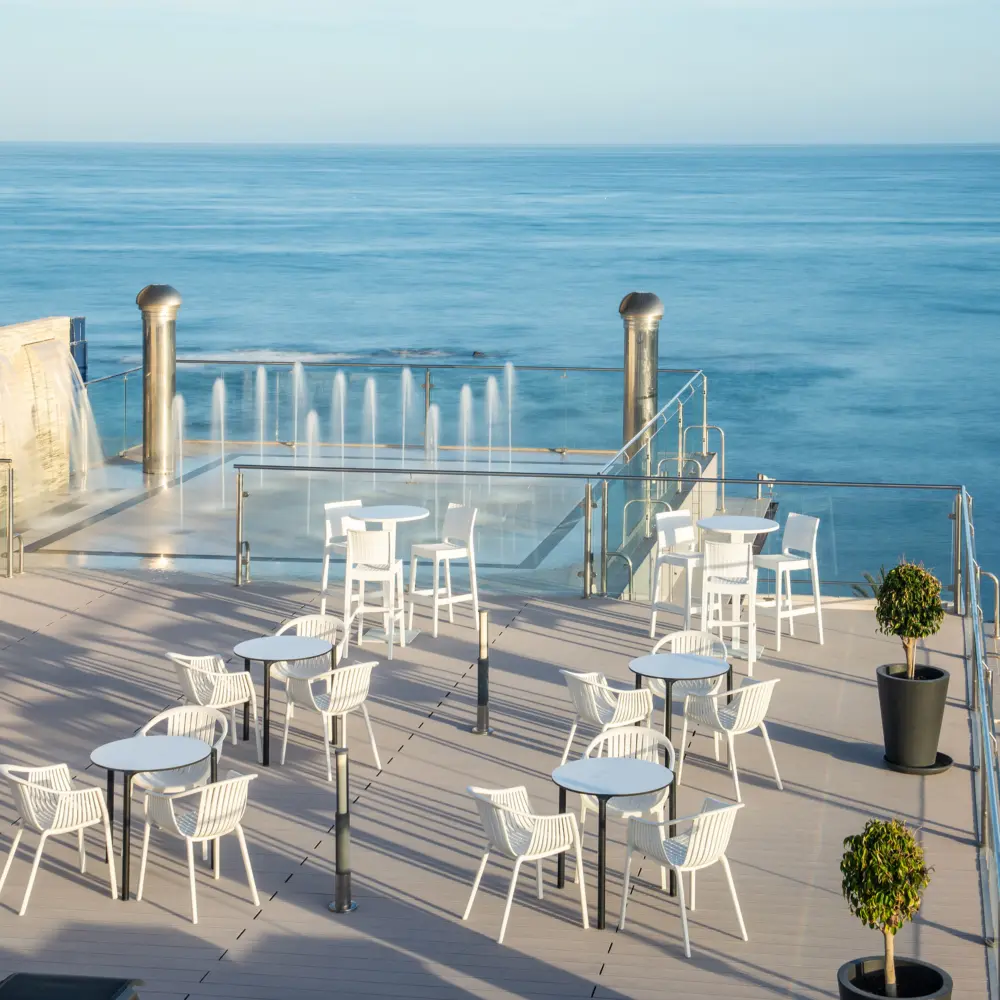 Une terrasse avec des chaises et fontaines offrant une vue sur la mer Méditerranée à l'hôtel Las Arenas à Benalmadena