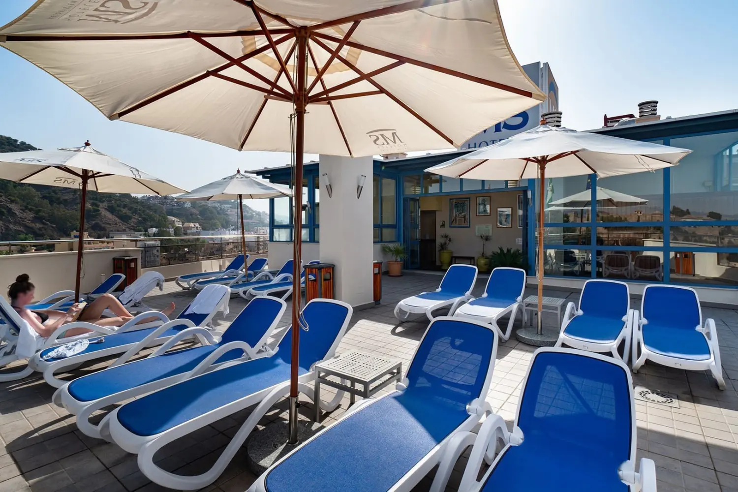 La terrasse située sur le toit de l'hôtel MS Maestranza Malaga Centre avec ses chaises longues sous un ciel ensoleillé