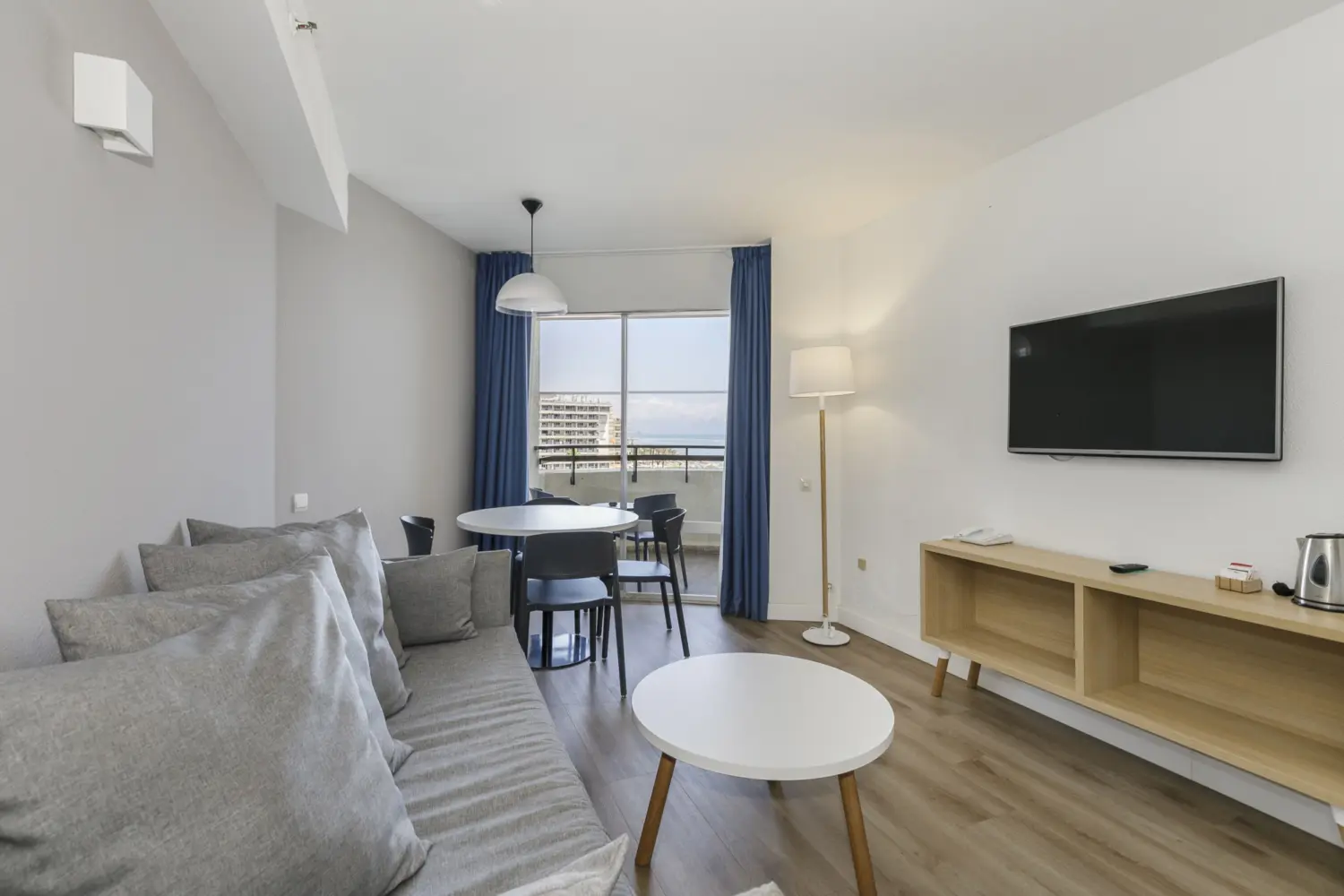Un salon avec sofa, télévision et table à manger, offrant une vue sur la mer depuis l'hôtel Sol Puerto Marina à Torremolinos