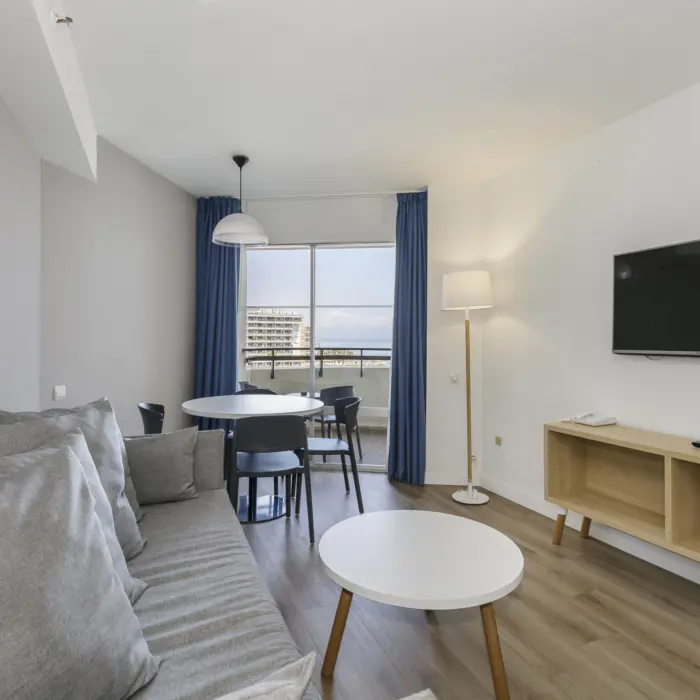 Un salon avec sofa, télévision et table à manger, offrant une vue sur la mer depuis l'hôtel Sol Puerto Marina à Torremolinos